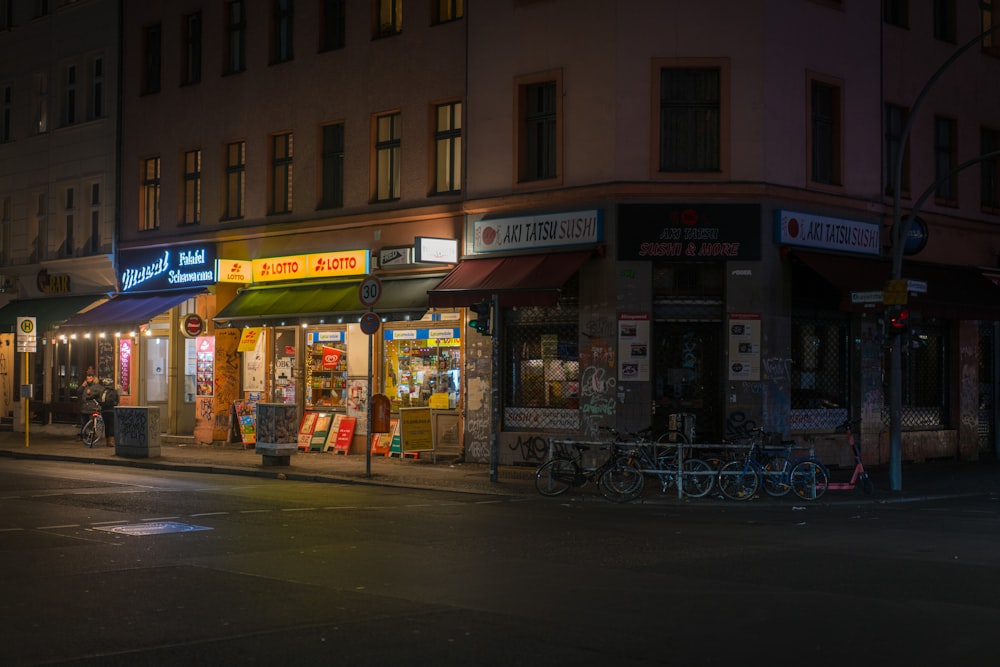 Persone che camminano sul marciapiede vicino a un edificio in cemento marrone durante la notte