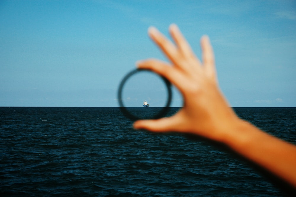 persons hand on blue ocean water during daytime