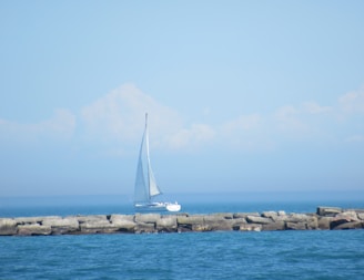 Sailboat cruising peacefully on the blue Mediterranean Sea near Barcelona coastline under clear skies.