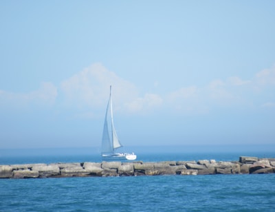 A sailboat gently rocking in a harbor with crisp, clear daylight.