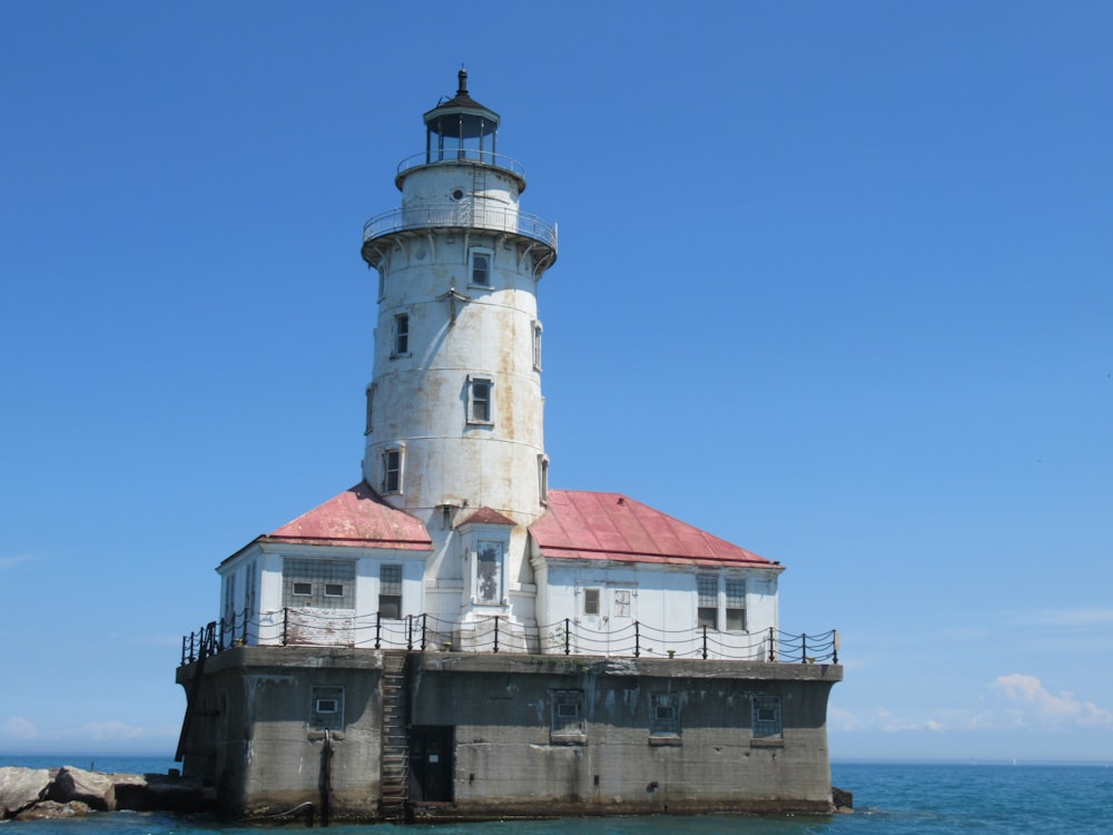 white and red concrete lighthouse under blue sky during daytime