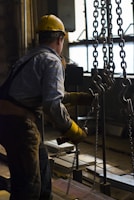man in blue dress shirt and brown pants standing on black metal frame