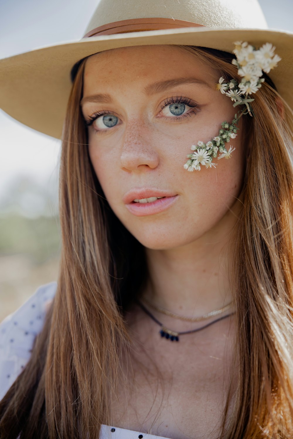 woman in white and black floral shirt with white flower on her ear