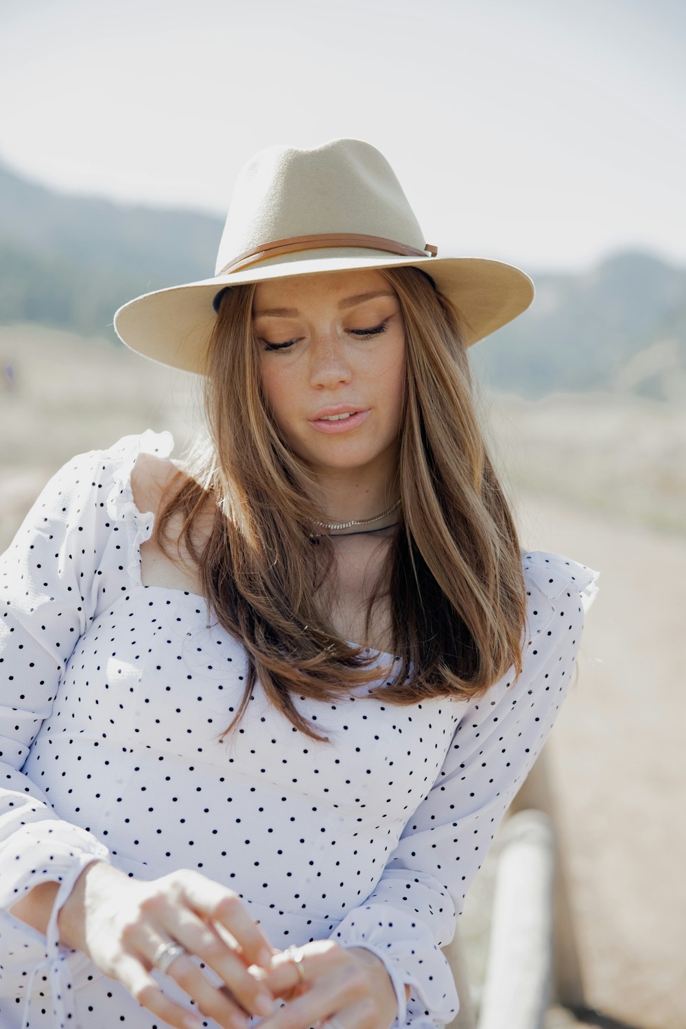 woman in white and red polka dot long sleeve shirt wearing brown hat