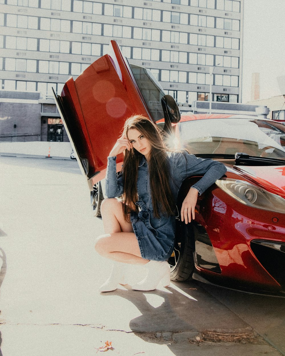 woman in blue denim jacket and white pants sitting on red car