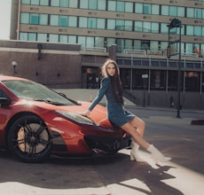 woman in blue long sleeve shirt and black skirt standing beside red car during daytime