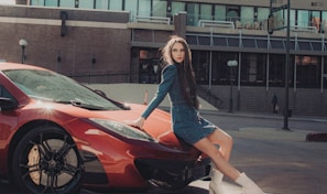 woman in blue long sleeve shirt and black skirt standing beside red car during daytime