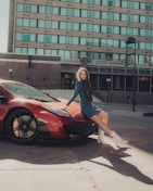 woman in blue long sleeve shirt and black skirt standing beside red car during daytime