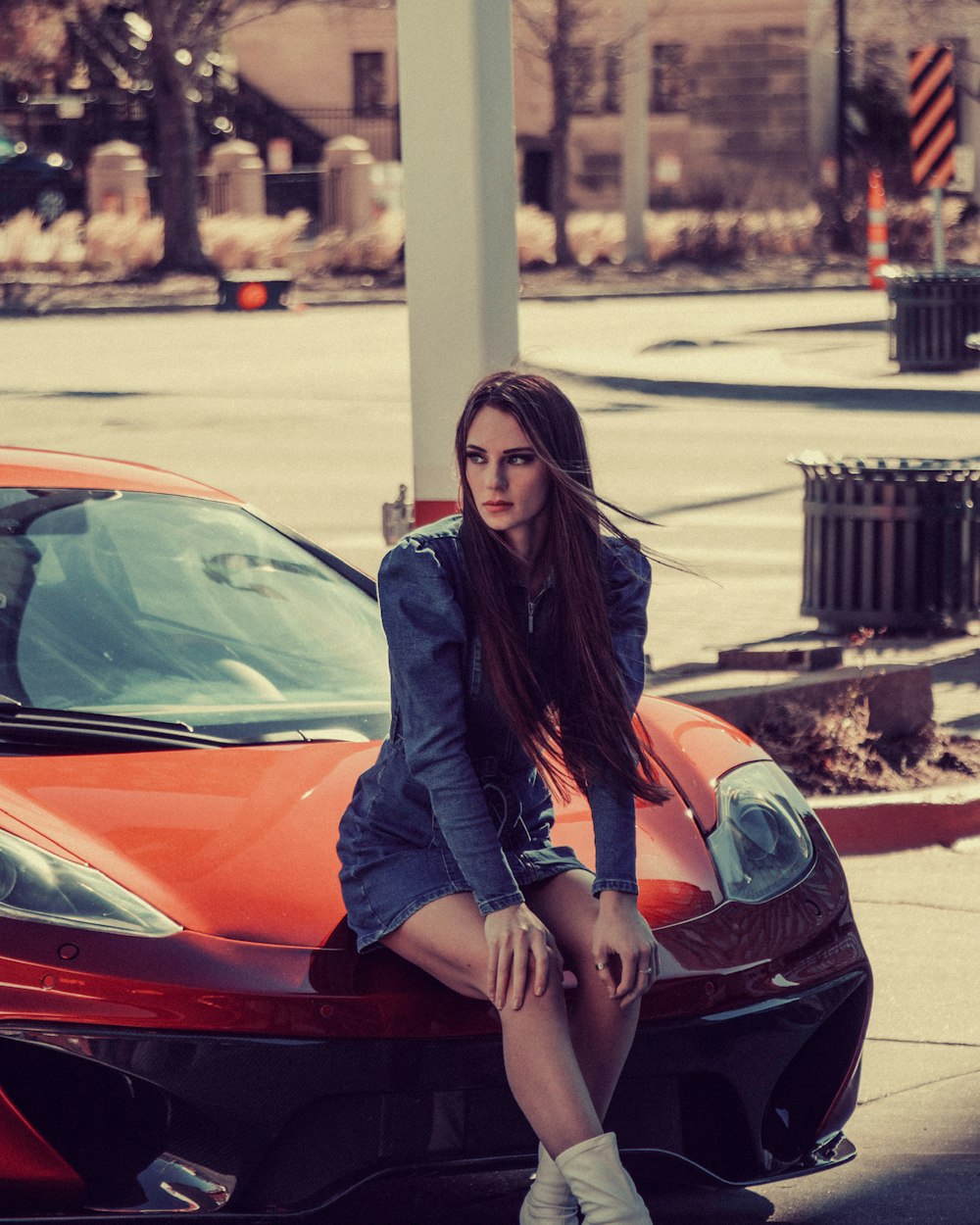 woman in black leather jacket sitting on red car