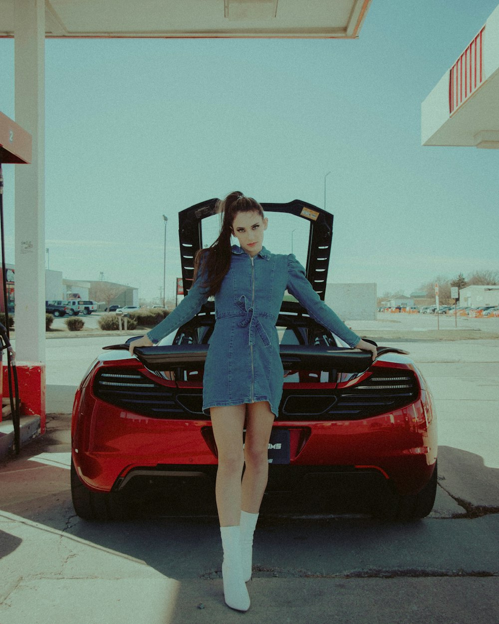 woman in blue long sleeve shirt and brown pants standing on red car