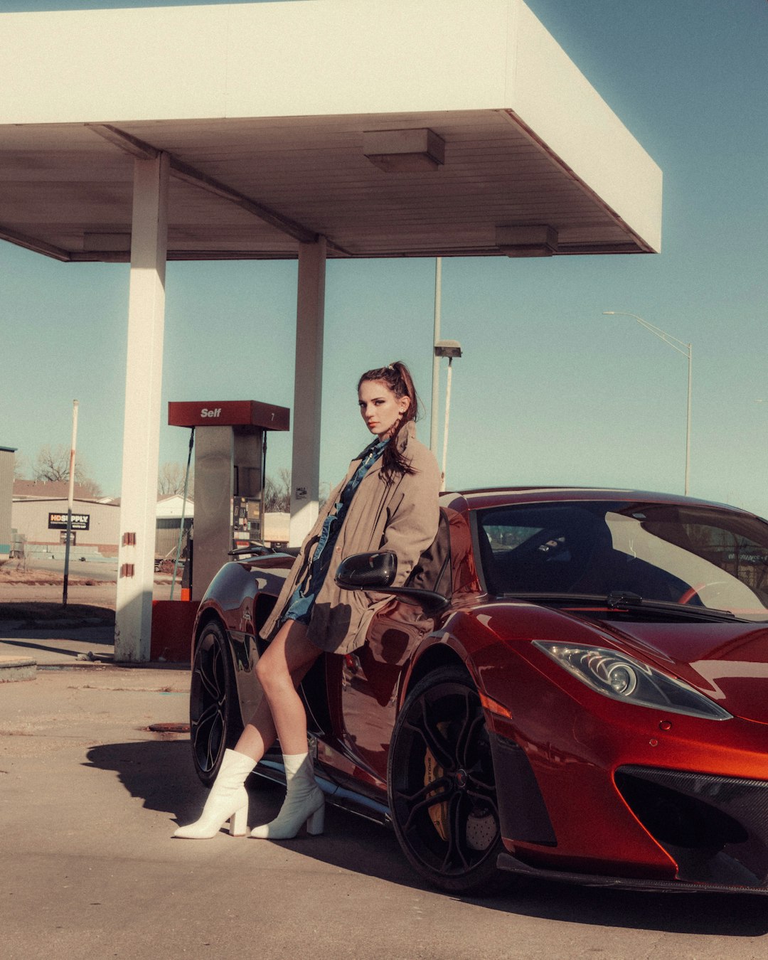 woman in brown jacket standing beside red car