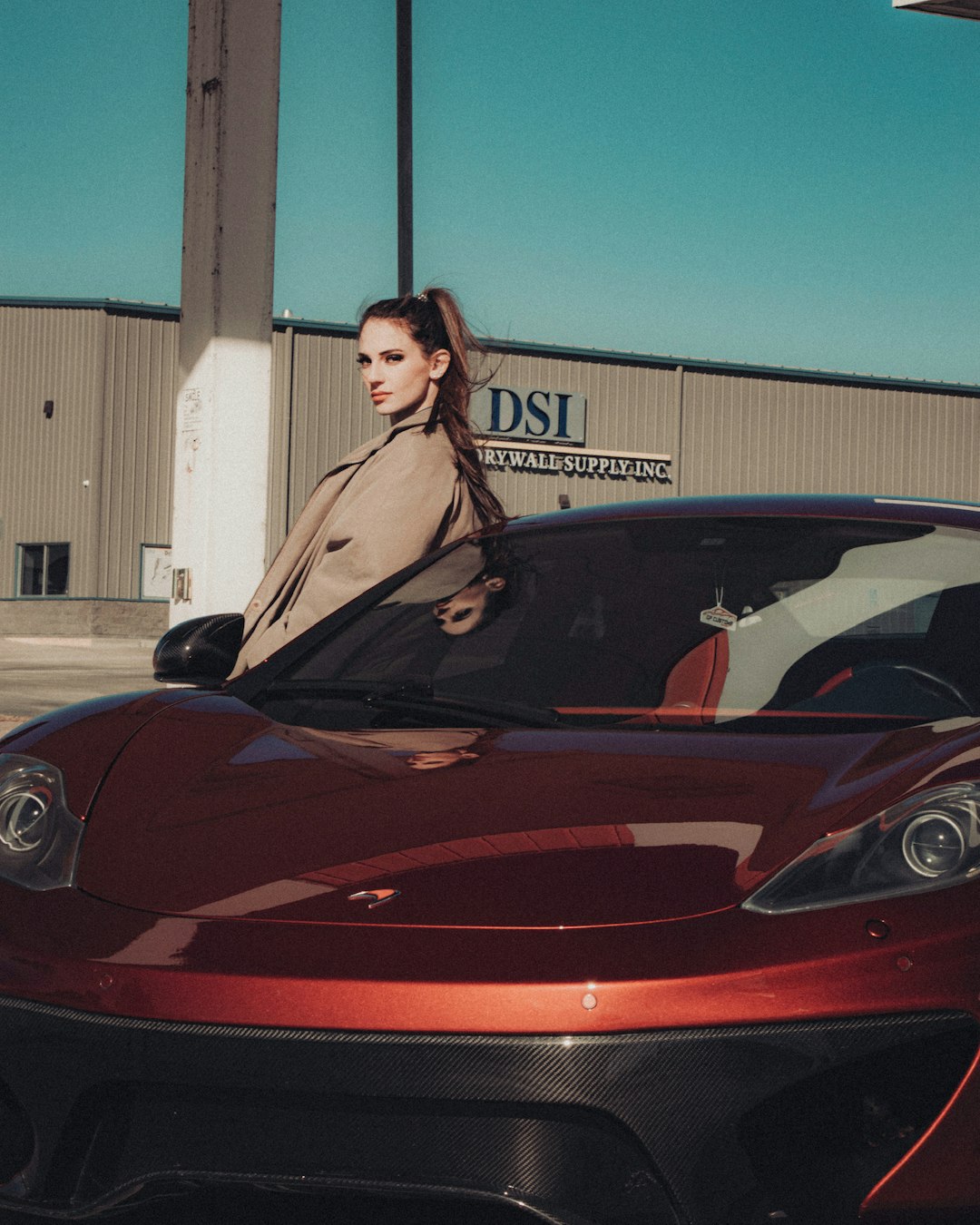 woman in black sleeveless dress standing beside red ferrari car
