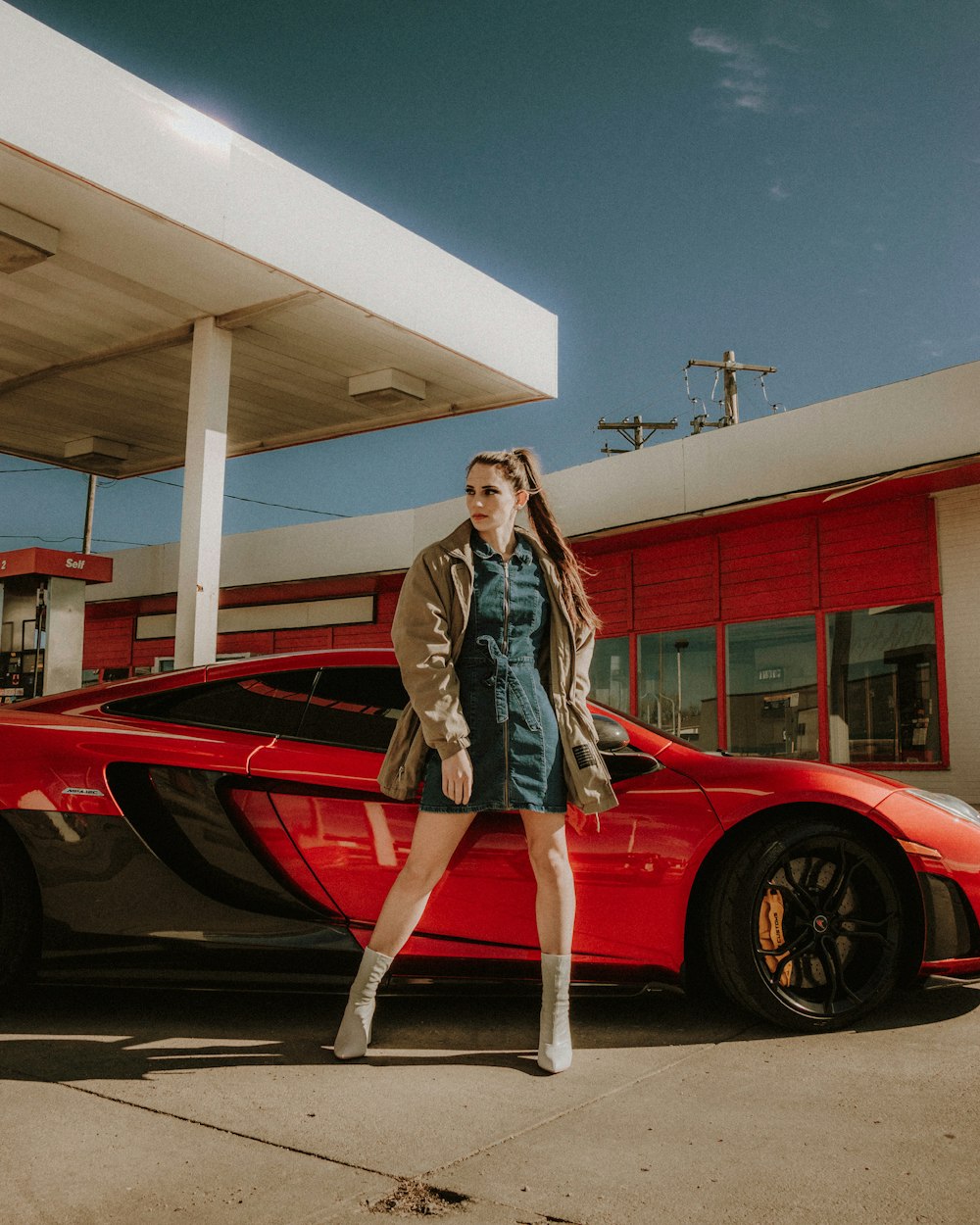 woman in black long sleeve shirt standing beside red car