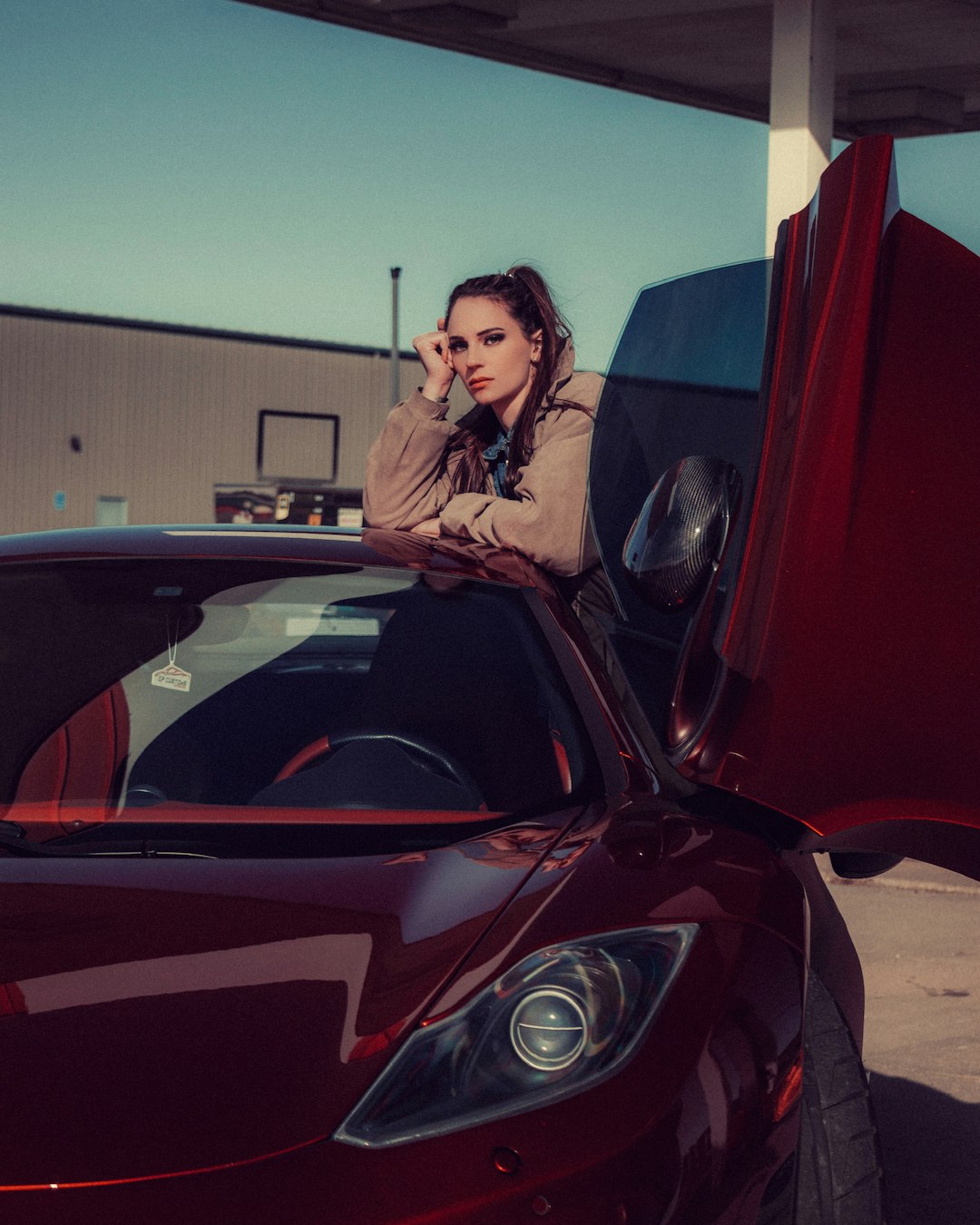 woman in black leather jacket standing beside red car during daytime