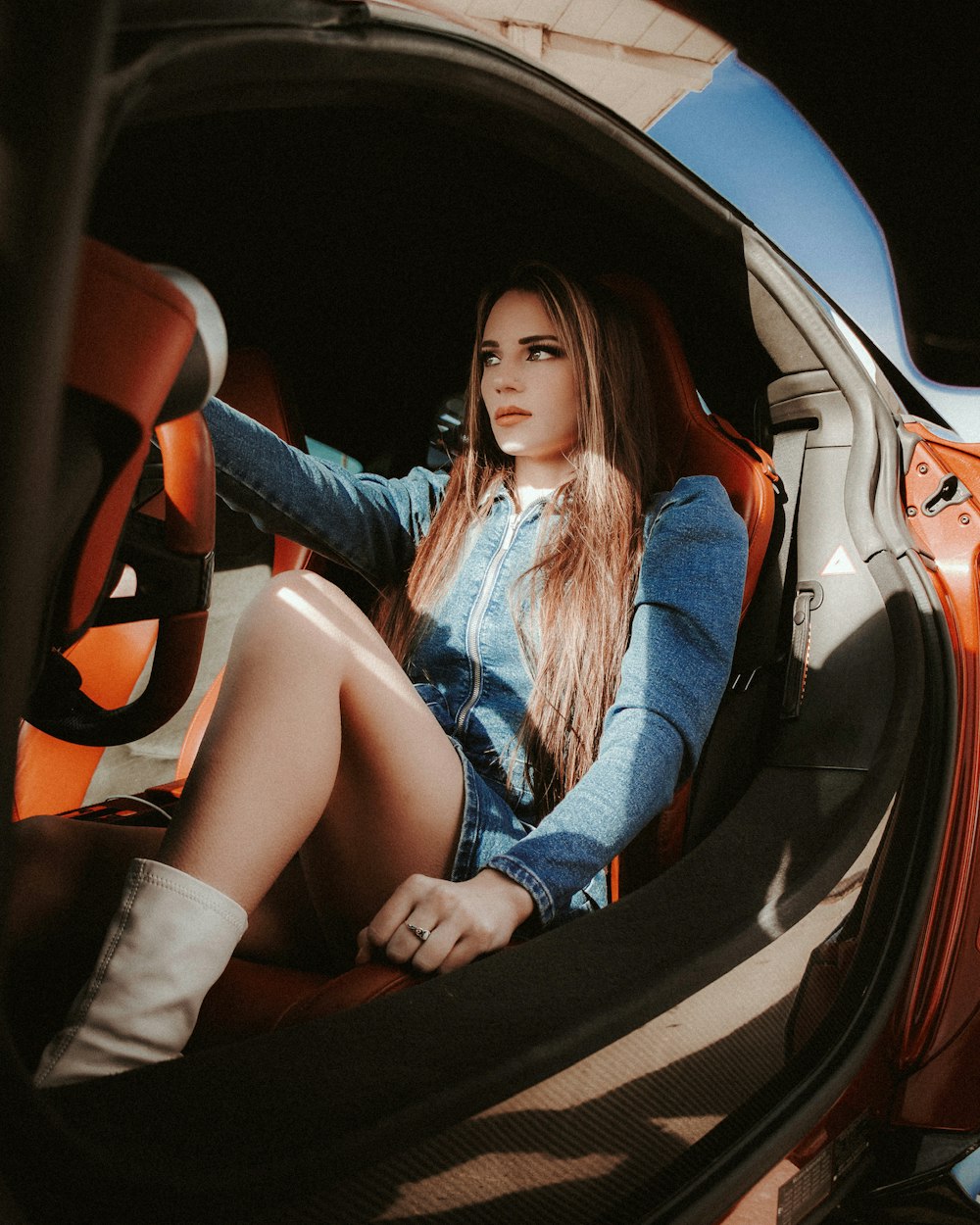 Mujer en chaqueta de mezclilla azul sentada en el asiento del automóvil
