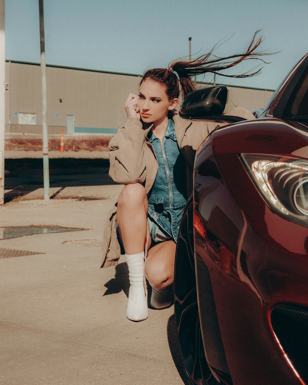 woman in brown coat sitting on red car