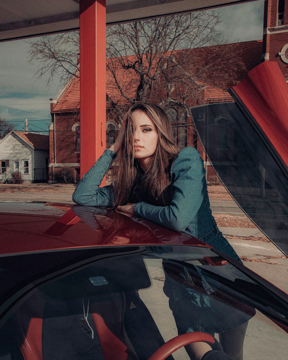 woman in gray long sleeve shirt leaning on red car