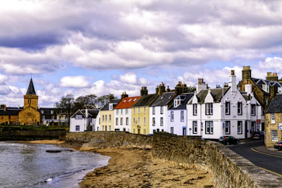 white and red concrete building beside body of water under cloudy sky during daytime Scotland