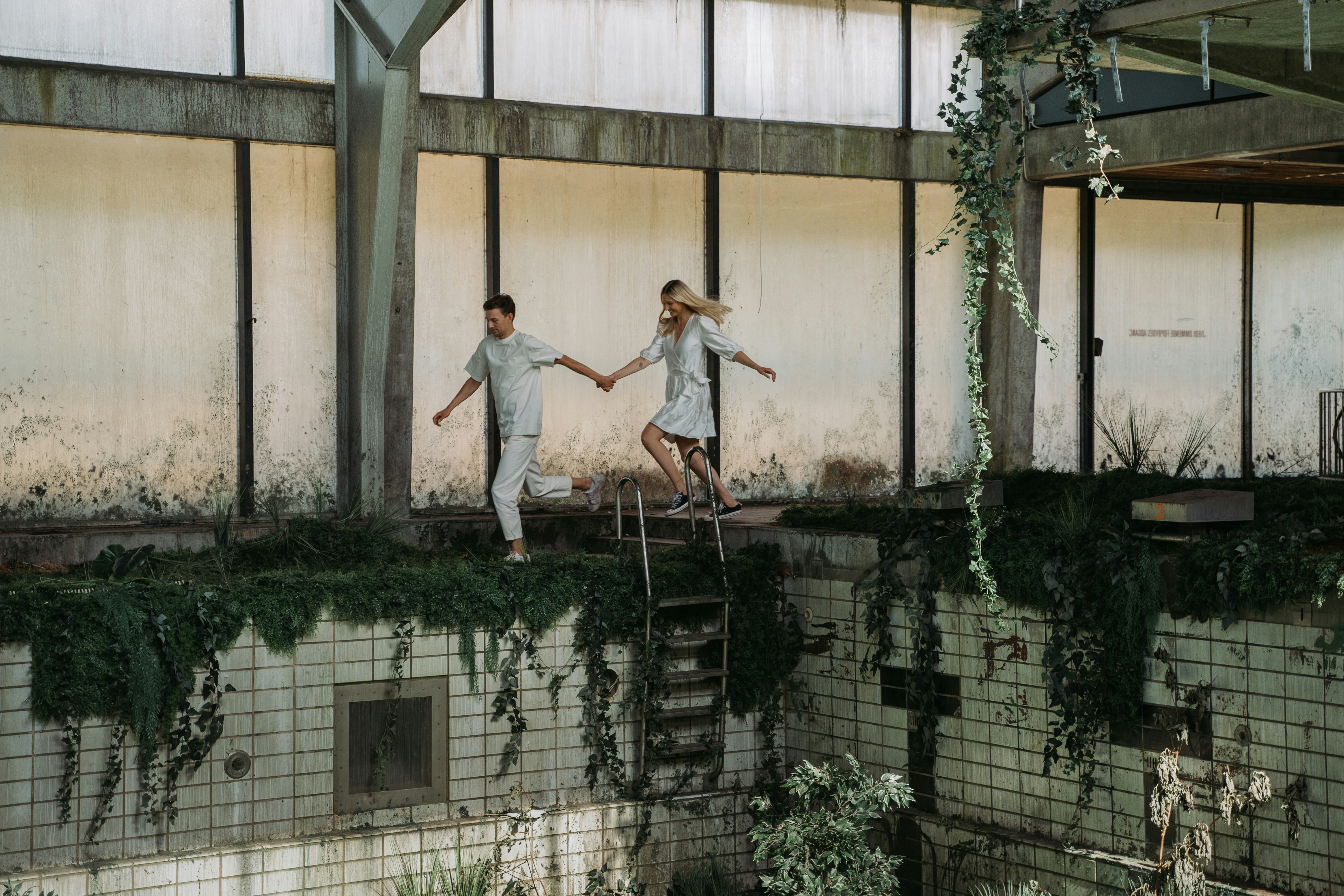 uomo in camicia bianca e jeans blu in denim in piedi sulla recinzione metallica nera durante il giorno