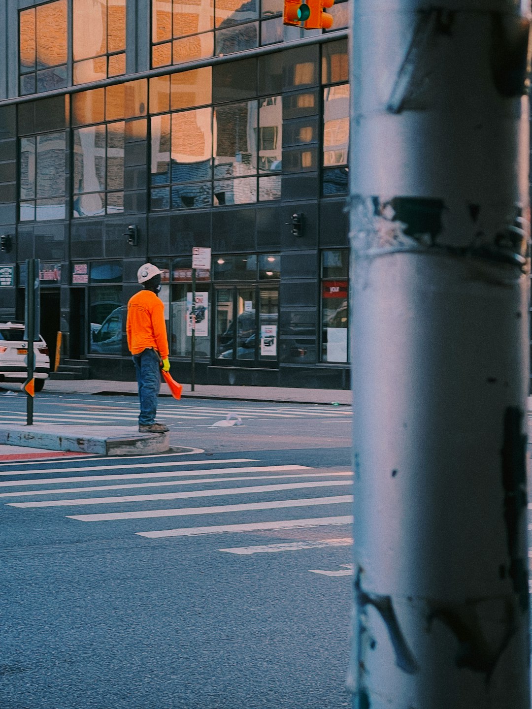 man in orange jacket and blue denim jeans standing on pedestrian lane during daytime