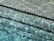 Rippling water in a swimming pool creates patterns of light and shadow. Black lane markers run horizontally across the pool, partially submerged and creating distinct lines against the clear blue water.