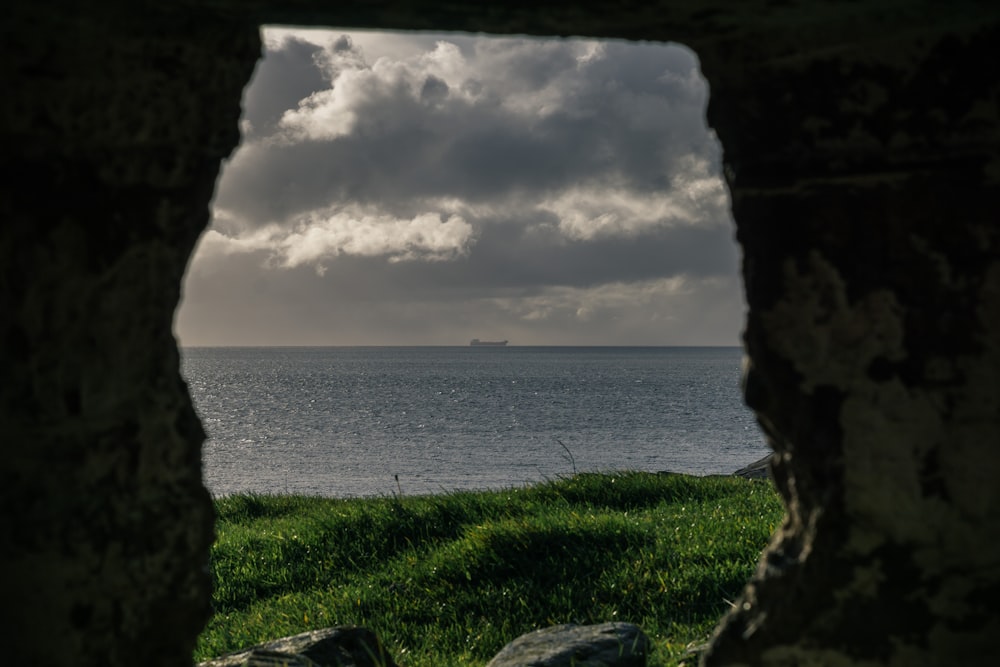 green grass field near body of water under cloudy sky during daytime