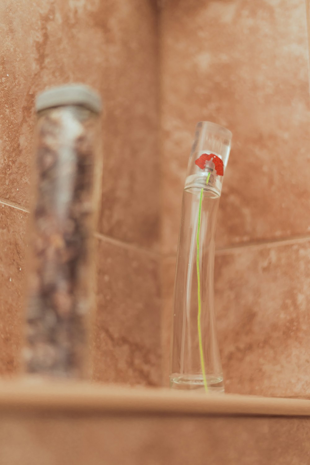 bouteille en verre transparent sur carreaux de céramique bruns