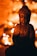 A bronze Buddha statue sits in focus against a blurred background of warm, glowing lights. The lighting casts gentle shadows, creating a serene and contemplative atmosphere.