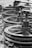 A series of industrial metal pulleys and cables in a black-and-white setting, showcasing a focus on machinery components. The metal appears worn and weathered, suggesting usage over time.