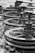 A series of industrial metal pulleys and cables in a black-and-white setting, showcasing a focus on machinery components. The metal appears worn and weathered, suggesting usage over time.