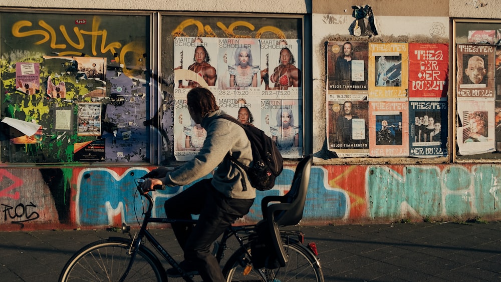 man and woman riding bicycle beside wall with graffiti