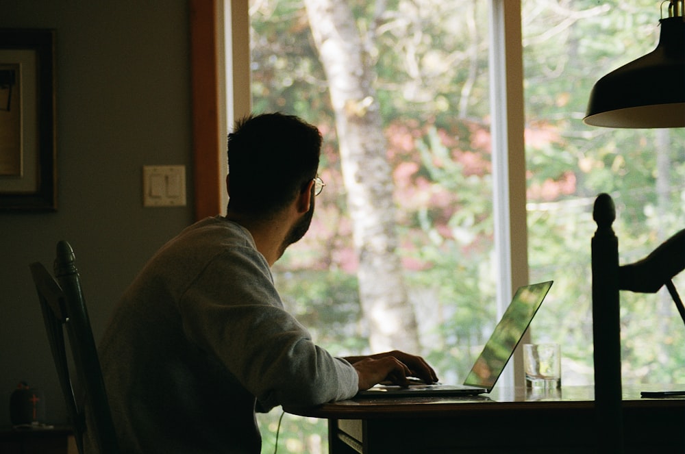 Mann in grauem Kapuzenpullover mit Laptop