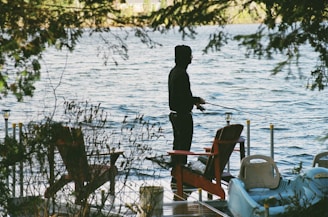 A family enjoying fishing together on the dock with a backdrop of lush green trees.