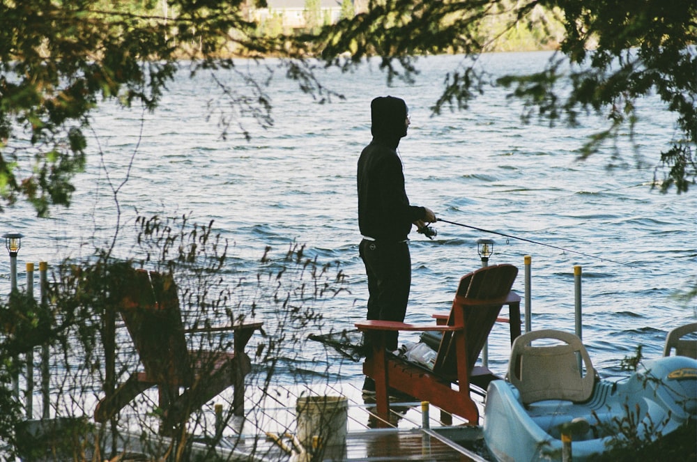 man in black jacket standing on brown wooden dock during daytime using Magic 71-12 King Kat Chicken Blood to catch catfish