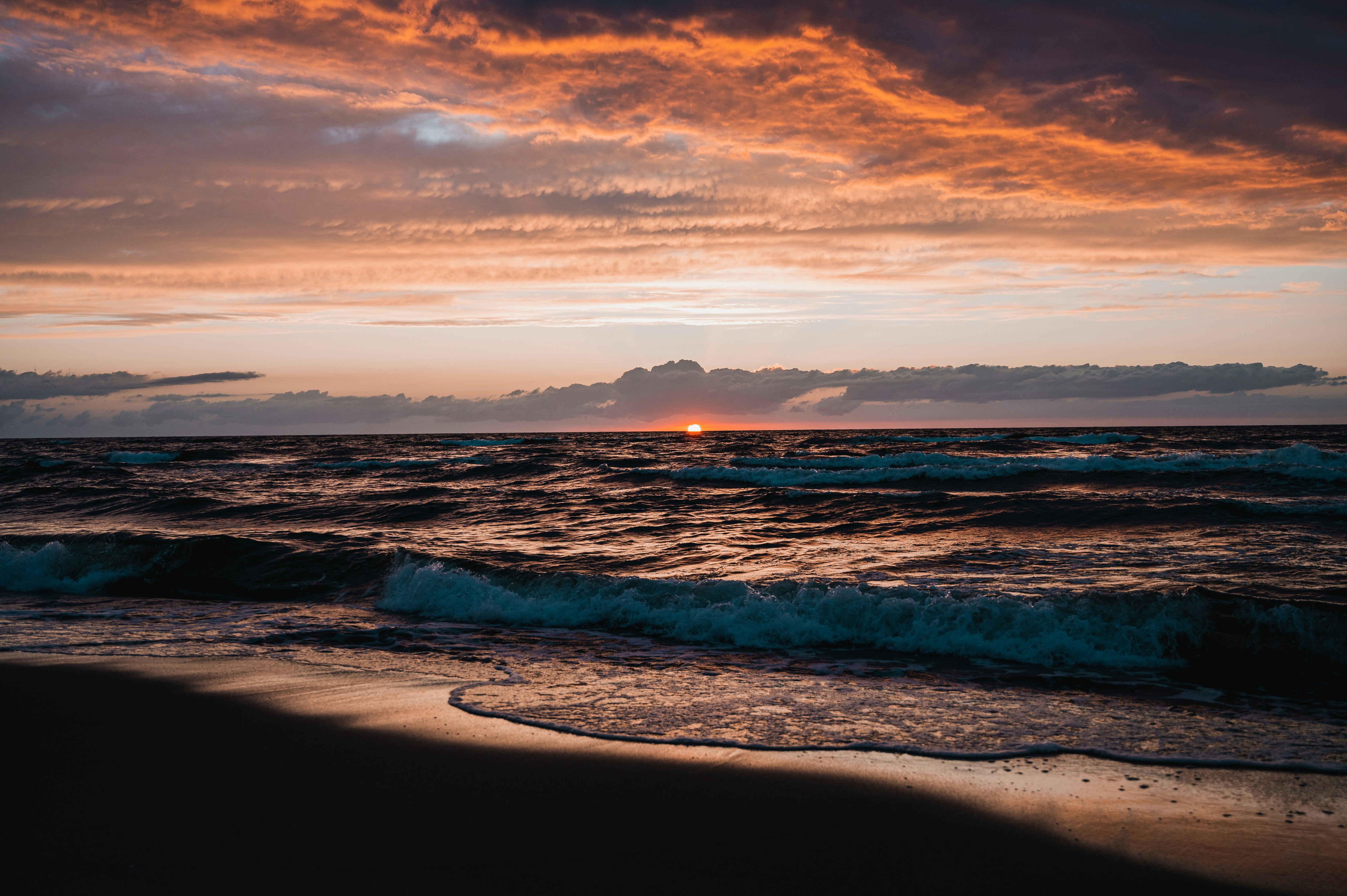 ocean waves crashing on shore during sunset