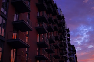 An apartment building with balconies and a city skyline in the background.