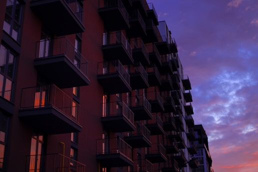 A modern apartment building overlooking a vibrant city skyline during sunset.