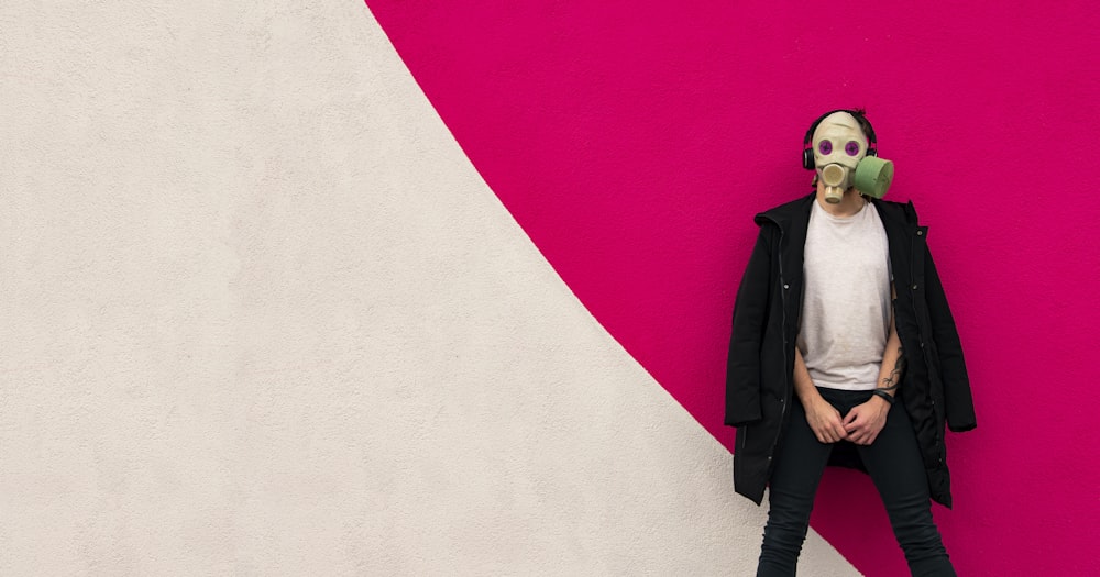 woman in black coat standing beside white wall