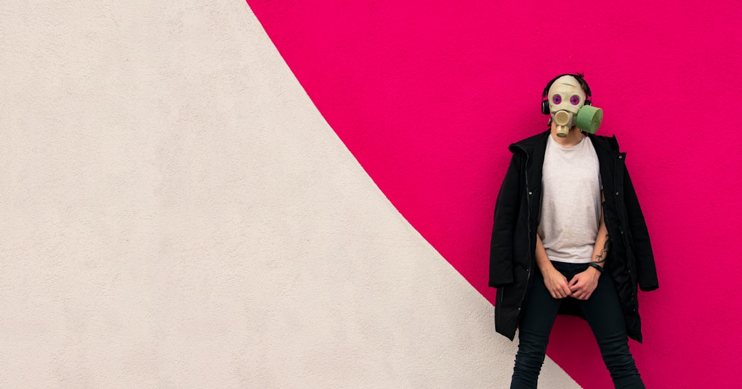 woman in black coat standing beside white wall