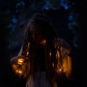 Close-up of a woman with fine dreadlocks bathed in warm golden light, embodying the salon's poetic beauty.