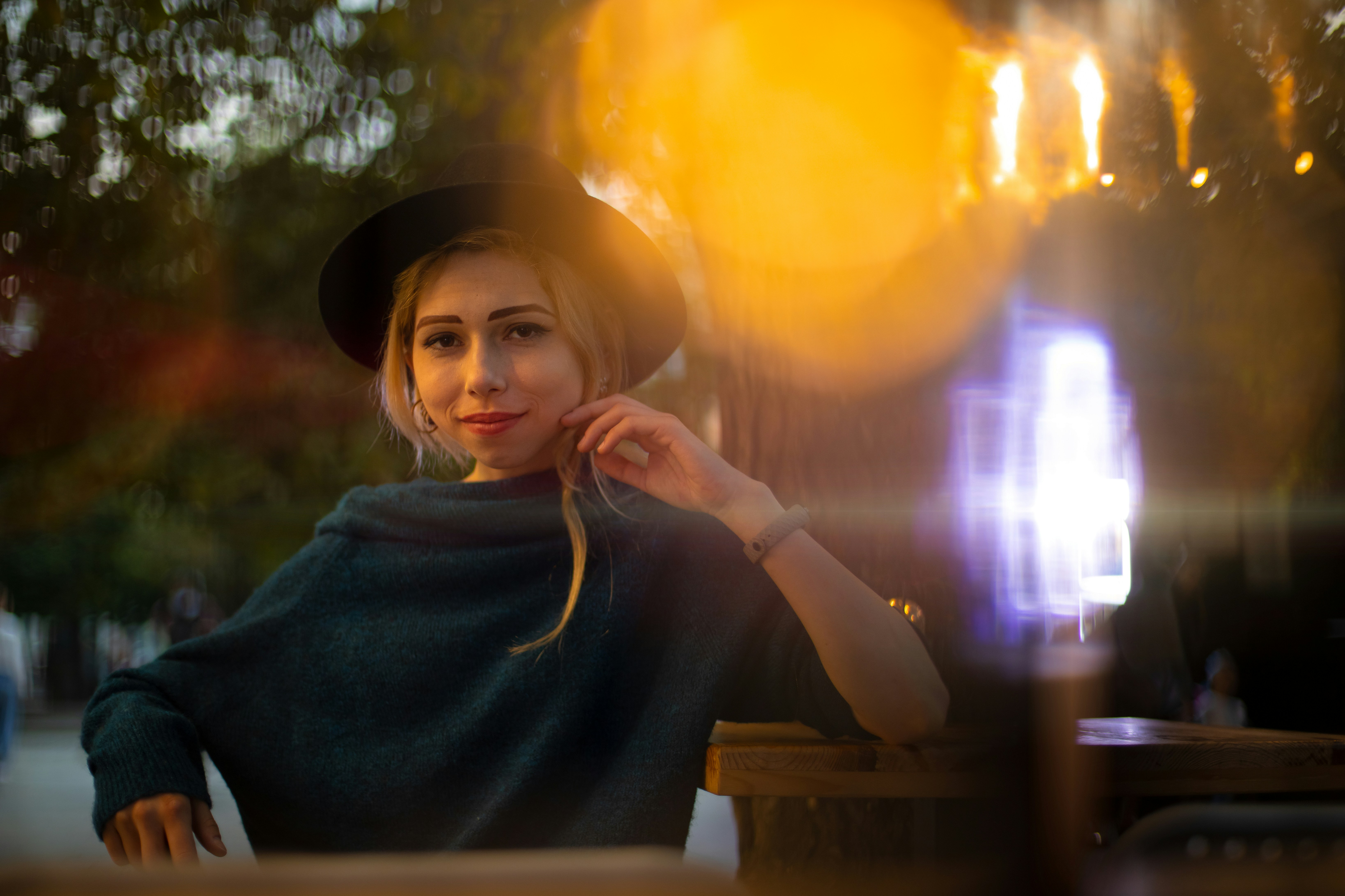 female portrait of beautiful young lady in black hat in evening city street park walking district romantic atmosphere with different bokeh and glare of lights in camera