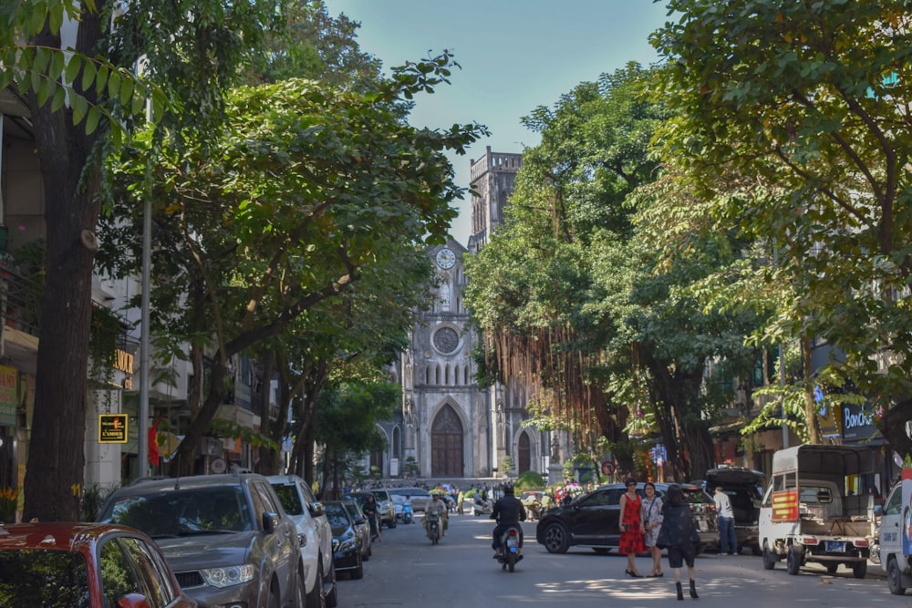 cars parked on sidewalk near green trees and buildings during daytime