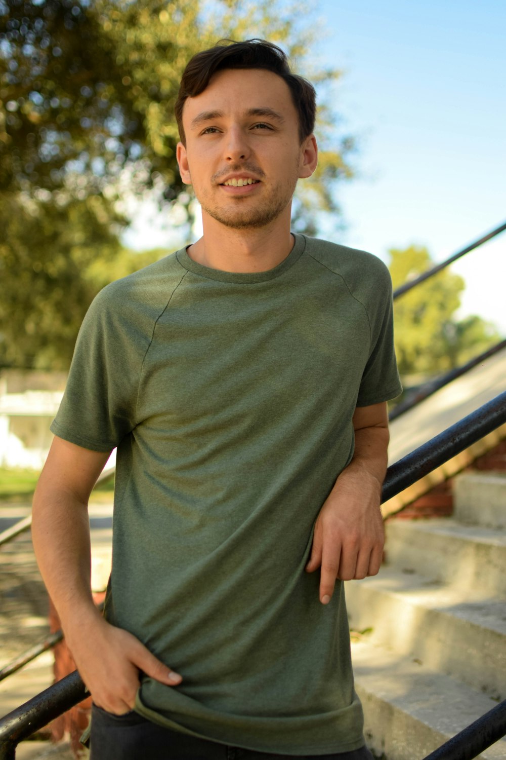 man in gray crew neck t-shirt standing beside black metal railings during daytime