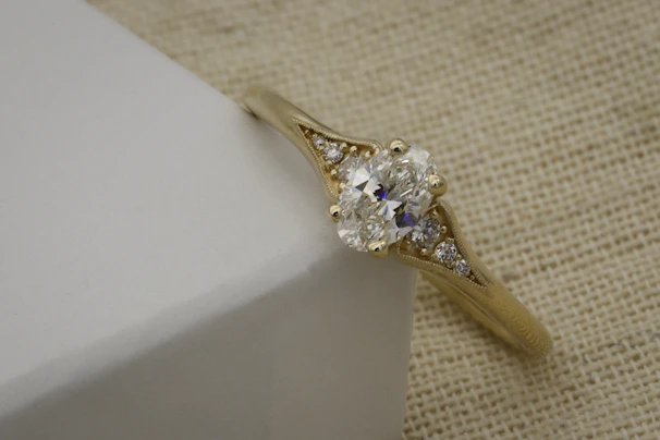 Close-up of a handcrafted 18k gold ring resting on a natural wooden surface, highlighting intricate details.