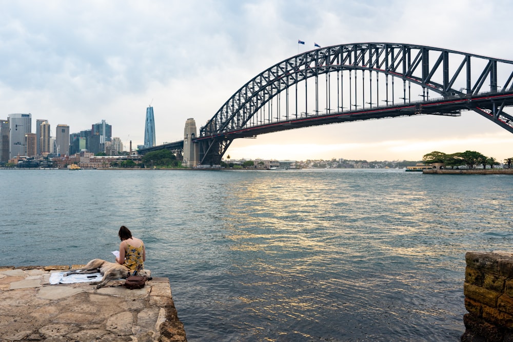 man in black shirt sitting on rock near body of water during daytime