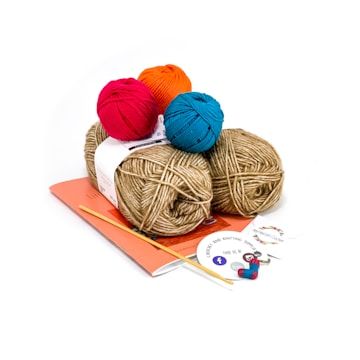 Four balls of yarn in vibrant pink, orange, blue, and beige sit atop a stack of papers. A crochet hook is placed alongside a round sticker and some small items.