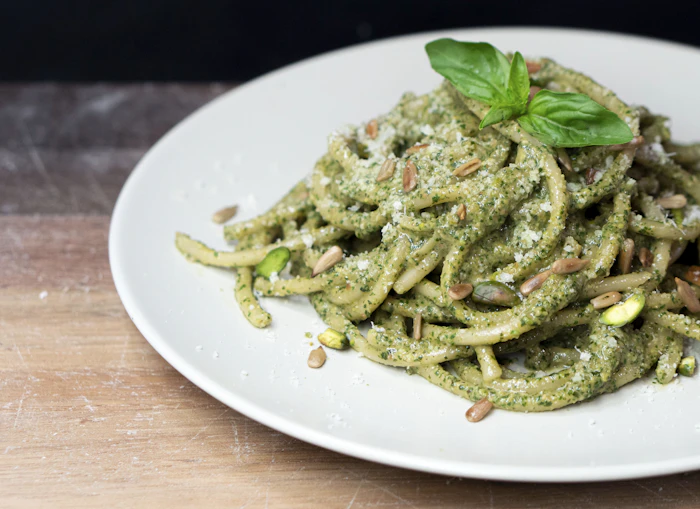 Pasta tossed in green basil pesto with pine nuts and basil