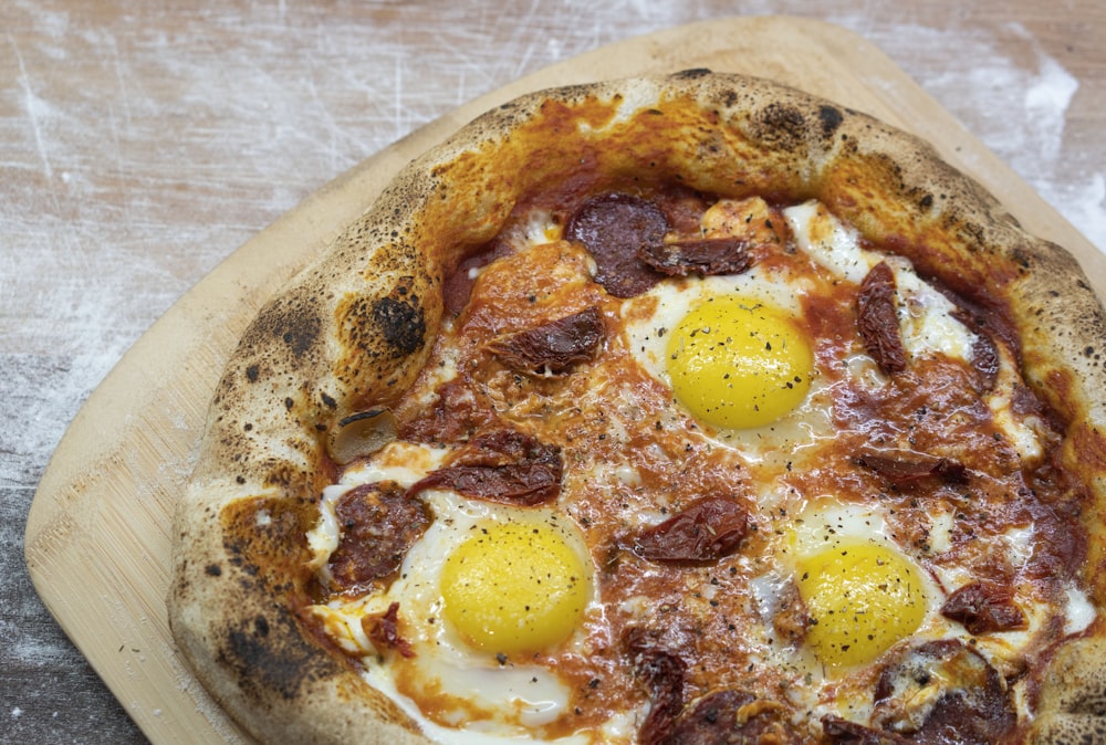 pizza with egg on white ceramic plate