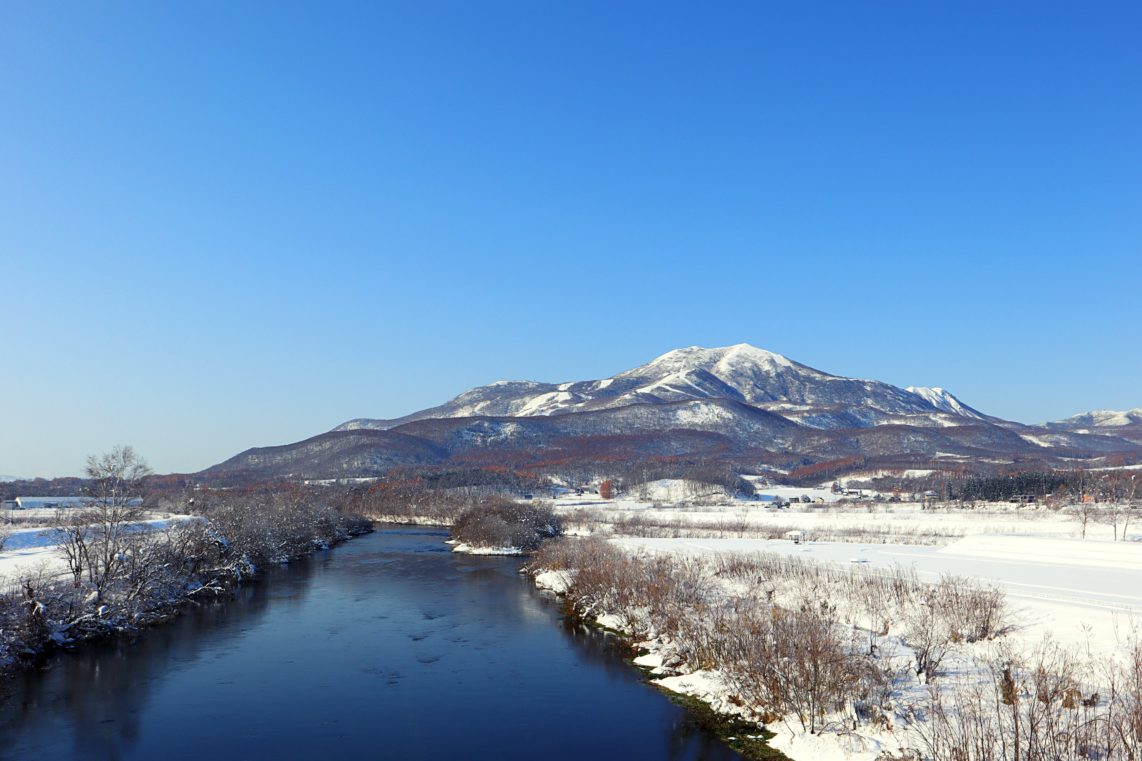 A winter river and the snow-capped Annupuri ski area, seen from Kutchan