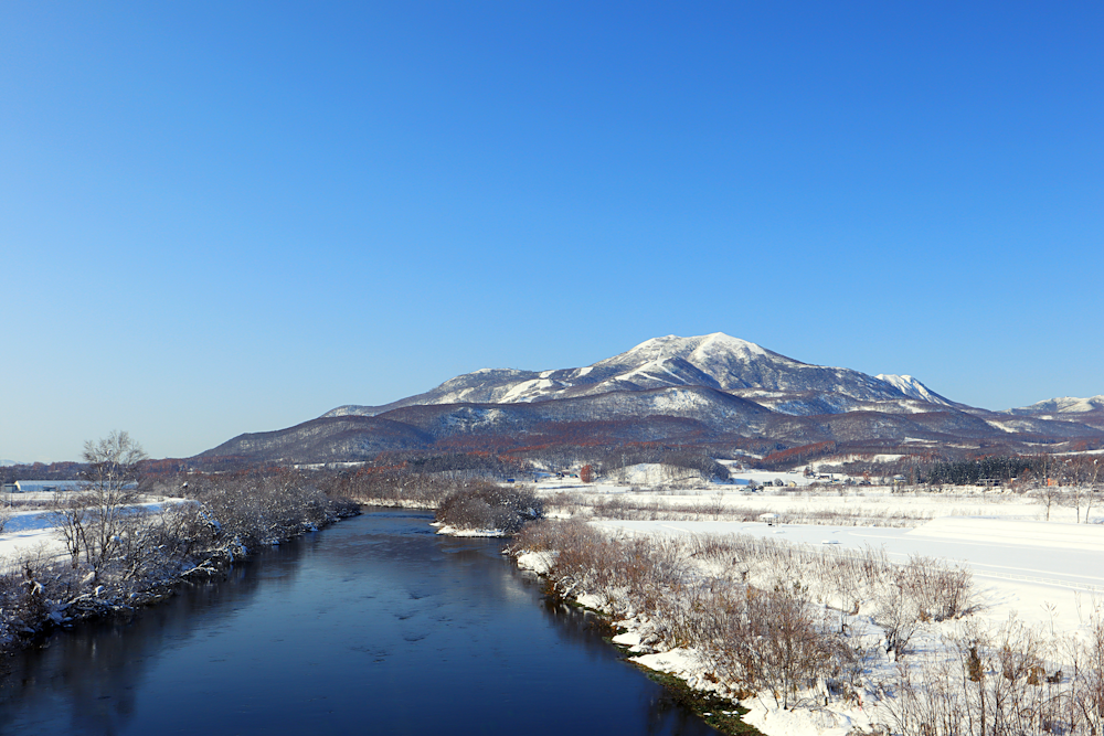 snow covered mountain near lake under blue sky during daytime